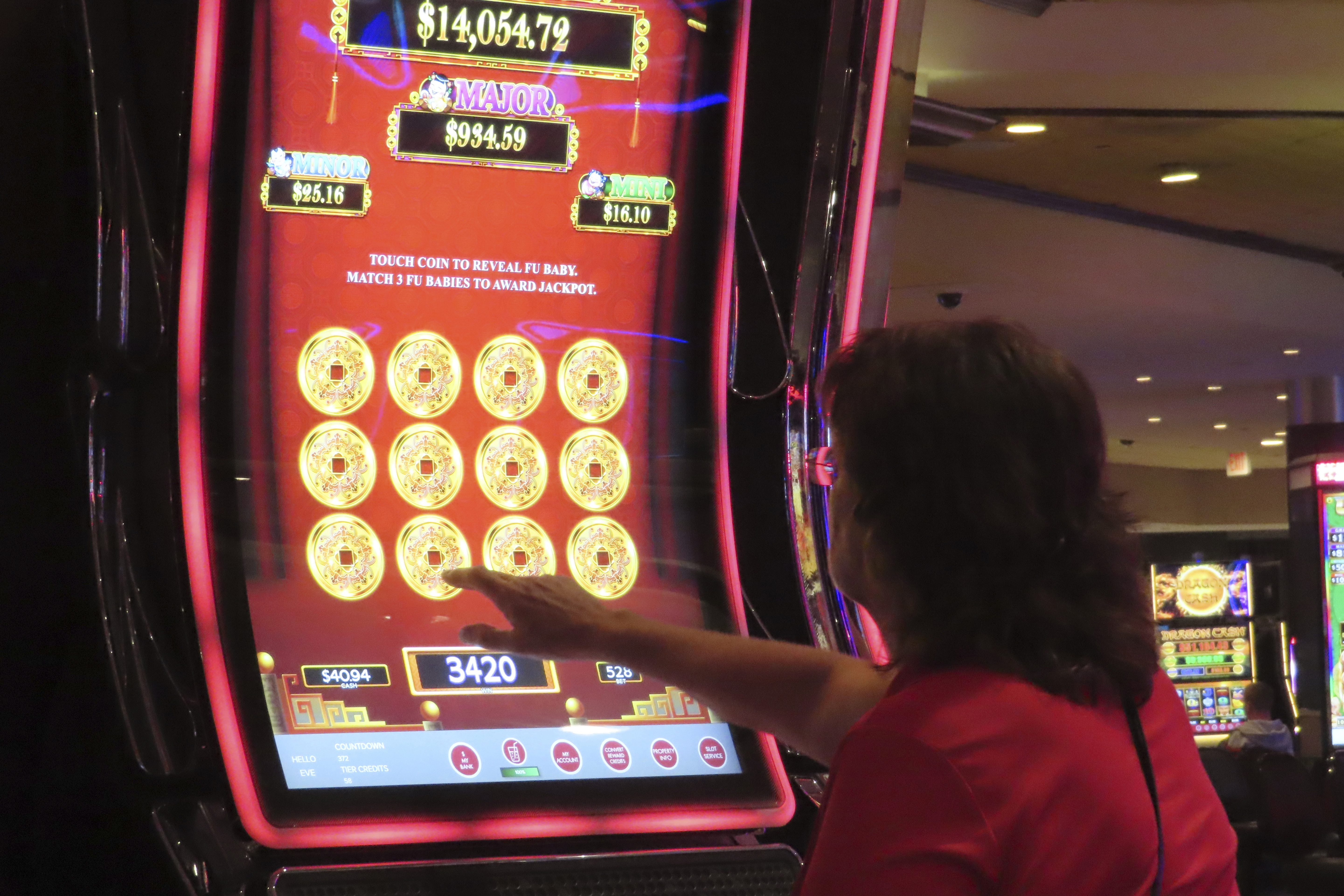 A gambler touches the screen of a slot machine at Harrah's casino in Atlantic City, N.J. on Sept. 29, 2023. Figures released on Tuesday, Feb. 20, 2024, by the American Gaming Association show that the U.S. commercial casino industry had its best year ever in 2023, winning $66.5 billion from gamblers. When figures from tribal casinos are tallied later this year, the combined total is expected to approach $110 billion for 2023. (AP Photo/Wayne Parry)